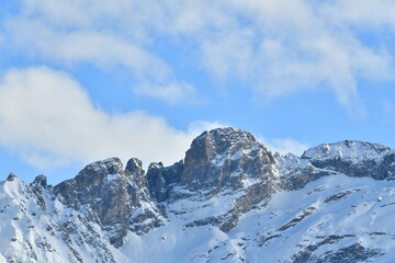 French alps on a sunny day under the clouds by winter covered with snow