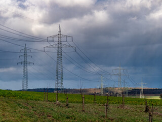 Strommasten einer &Uuml;berlandleitung unter dunklem Wolkenhimmel