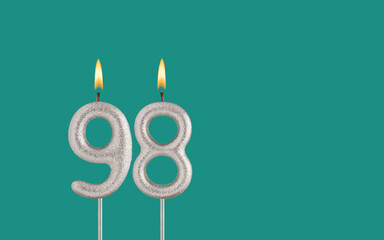 Birthday candle number 98 - Card on a green background.