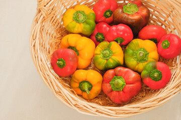 Peppers in a straw basket. Orange and red ripe vegetables. Top view. Place for text.