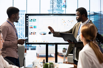 In a high end boardroom, employees gather to brainstorm ideas and create strategies, analyzing statistics to drive business development and ensure successful project management. Enterprise solutions.