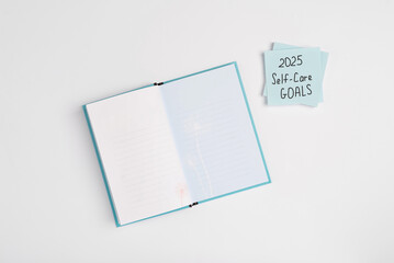 Paper note with words 2025 Self Care Goals on a white minimal background. Concept of goals and plans for the new year. Concept of mental health care, top view