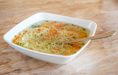broth with noodles, decorated with parsley and carrots
