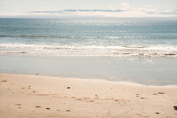Serene Beach Horizon with Mountains and Clouds Across the Sea