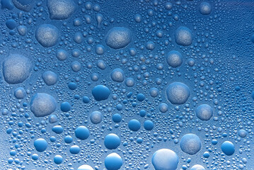A mesmerizing close-up of water droplets on a blue surface, showcasing various sizes and textures, creating a soothing and refreshing visual effect.