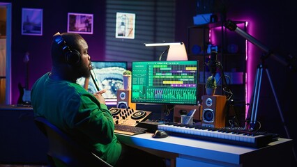 Confident music composer mixing sounds on digital audio software, creating a cool atmosphere in his...