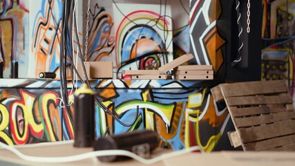 Close up shot of electric cables hanging in trashed desolate building with graffiti drawings on walls. Spraying paint cans in underground criminal den used as headquarters by teenagers