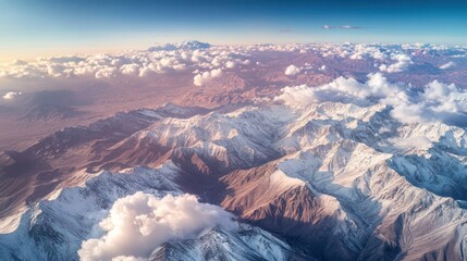 Obraz premium Aerial sunset view of snow-capped mountains, clouds, and desert landscape; travel brochure