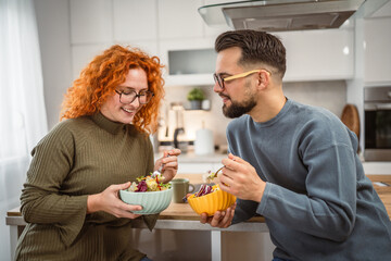 boyfriend and girlfriend eat salad and enjoy at breakfast at home