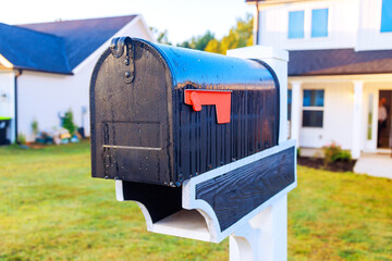 Mailbox in front of contemporary house receives sunlight, highlighting its black surface, vibrant...