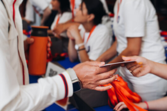 Process of checking in on conference congress forum event, registration desk table, visitors and attendees receiving lanyard with name badge and entry wristband bracelet and register electronic ticket