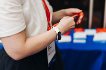 Process of checking in on conference congress forum event, registration desk table, visitors and attendees receiving lanyard with name badge and entry wristband bracelet and register electronic ticket