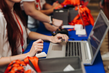 Process of checking in on conference congress forum event, registration desk table, visitors and attendees receiving lanyard with name badge and entry wristband bracelet and register electronic ticket