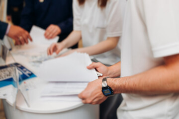 Process of checking in on conference congress forum event, registration desk table, visitors and attendees receiving lanyard with name badge and entry wristband bracelet and register electronic ticket