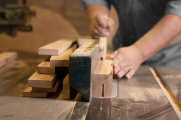 A male carpenter cutting wood with a circular saw in a carpentry sho