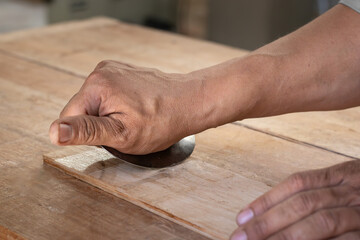 the carpenter works with manual equipment to polish wood