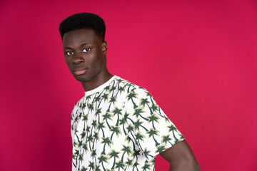 Obraz premium Young black man posing with tropical shirt on pink background