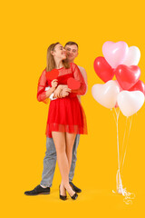 Lovely couple with paper hearts and balloons on yellow background. Valentine's Day celebration