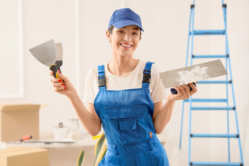 Female decorator with putty knives in room