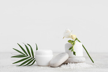 Composition with cosmetic products, sea, salt, spa stones and flower on light table
