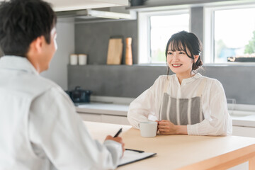 契約書・同意書の説明を聞く主婦と説明する作業着姿の営業マンの男性
