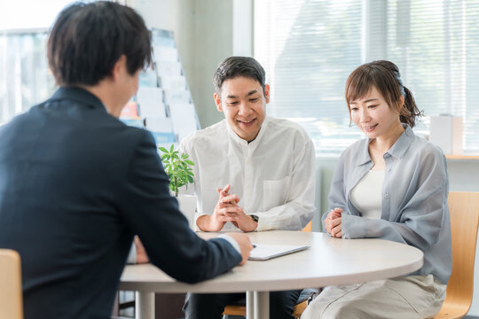 ショールーム・商談スペースで話を聞く夫婦と接客するビジネスマン
