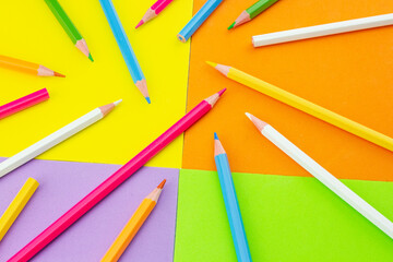 Scattered colored pencils on bright, playful art supplies.