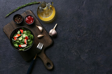 Bowl of salad with crab sticks, spinach, cucumber and ingredients on black grunge background © Pixel-Shot