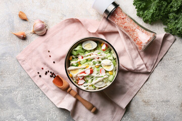 Bowl of salad with crab sticks, iceberg leaves, corn, cucumber and quail eggs on grey grunge background © Pixel-Shot