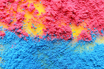 Scattered color powder pigments on yellow background, closeup