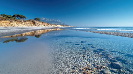 Clear water, sandy beach, mountain backdrop.