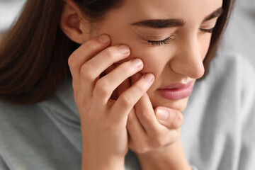 Young woman suffering from toothache at home, closeup