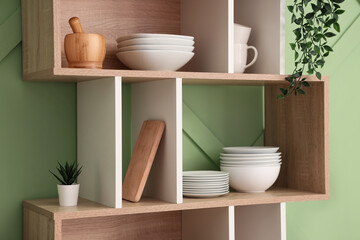 Shelves with clean plates and bowls in stylish kitchen, closeup