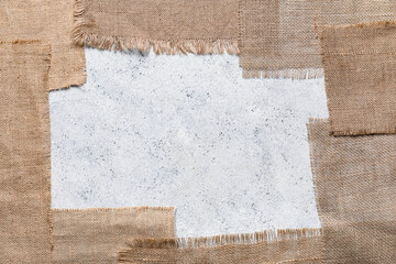 Frame made of burlap fabric pieces on light background