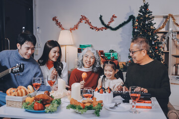 Multi-Generation Family Celebrate Christmas At Home Wearing Santa Hats And Antlers Opening Presents