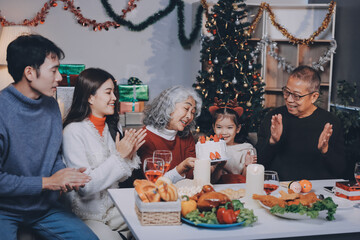 Multi-Generation Family Celebrate Christmas At Home Wearing Santa Hats And Antlers Opening Presents