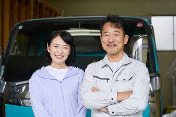 トラックの前に立つ作業員の夫婦のポートレート