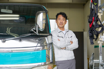 トラックの横に立つ男性作業員のポートレート　カメラ目線