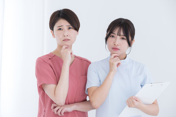 考える悩むポーズで顎に手を当てる看護師やドクターのイメージ