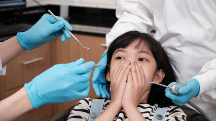 Asian girl patient fear and worry about tooth pain when pediatric dentist examines toothache with...