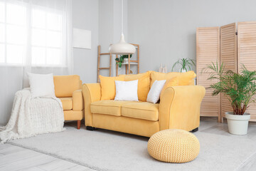 Interior of stylish living room with cozy yellow armchair, sofa and pouf