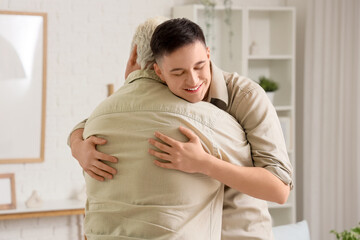 Young man hugging his father at home