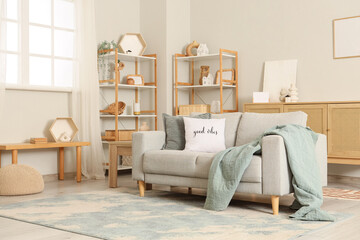Interior of light living room with grey sofa and shelf units