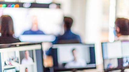 Virtual Conference Blur – A blurred background of a virtual business conference with multiple screens displayed.
