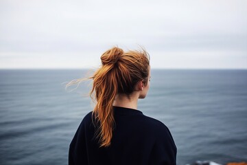 Fototapeta premium The somber scenery features a woman observing the tumultuous waters.