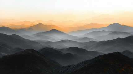 Fototapeta premium Misty mountain range at sunrise, layers of hills in warm sunset light.
