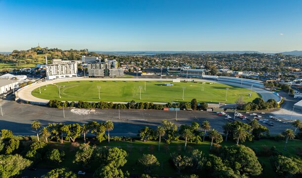High-angle view of Alexandra Park, Auckland, New Zealand. Empty race track and parking lot. Cityscape in background. Alexandra Raceway Park, Auckland, New Zealand - Powered by Adobe