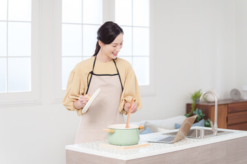 パソコンを見て料理する女性