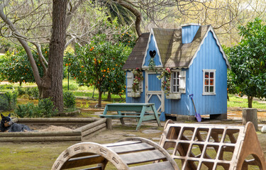 A charming wooden playhouse for children, set in a picturesque garden with a sandbox nearby, creating an ideal space for kids to play and develop creativity.