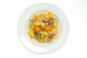 Sweet and sour stir-fried pineapple with pork on a white isolated background, Top view.